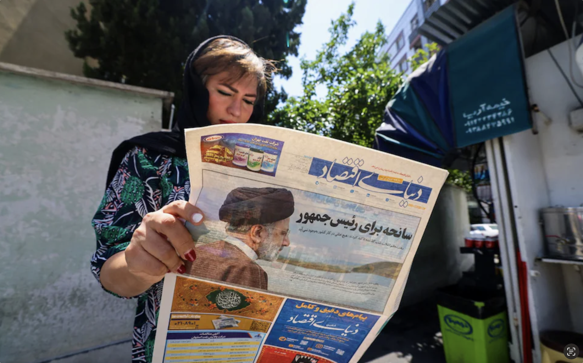 امرأة تقرأ صحيفة يتصدرها نبأ مصرع الرئيس الإيراني إبراهيم رئيسي