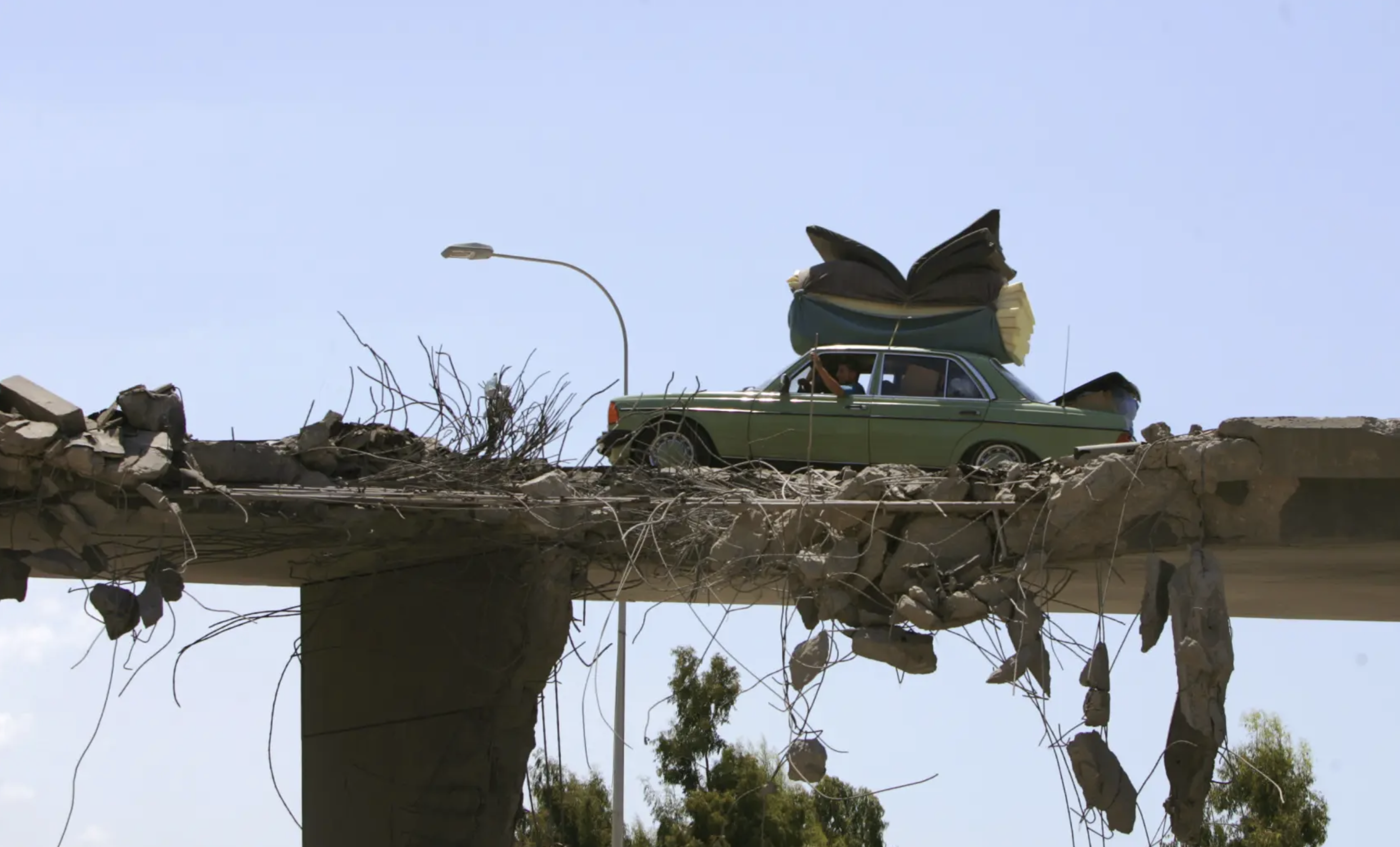 سيارة تعبر فوق جسر مهدم في لبنان خلال حرب تموز (يوليو) 2006