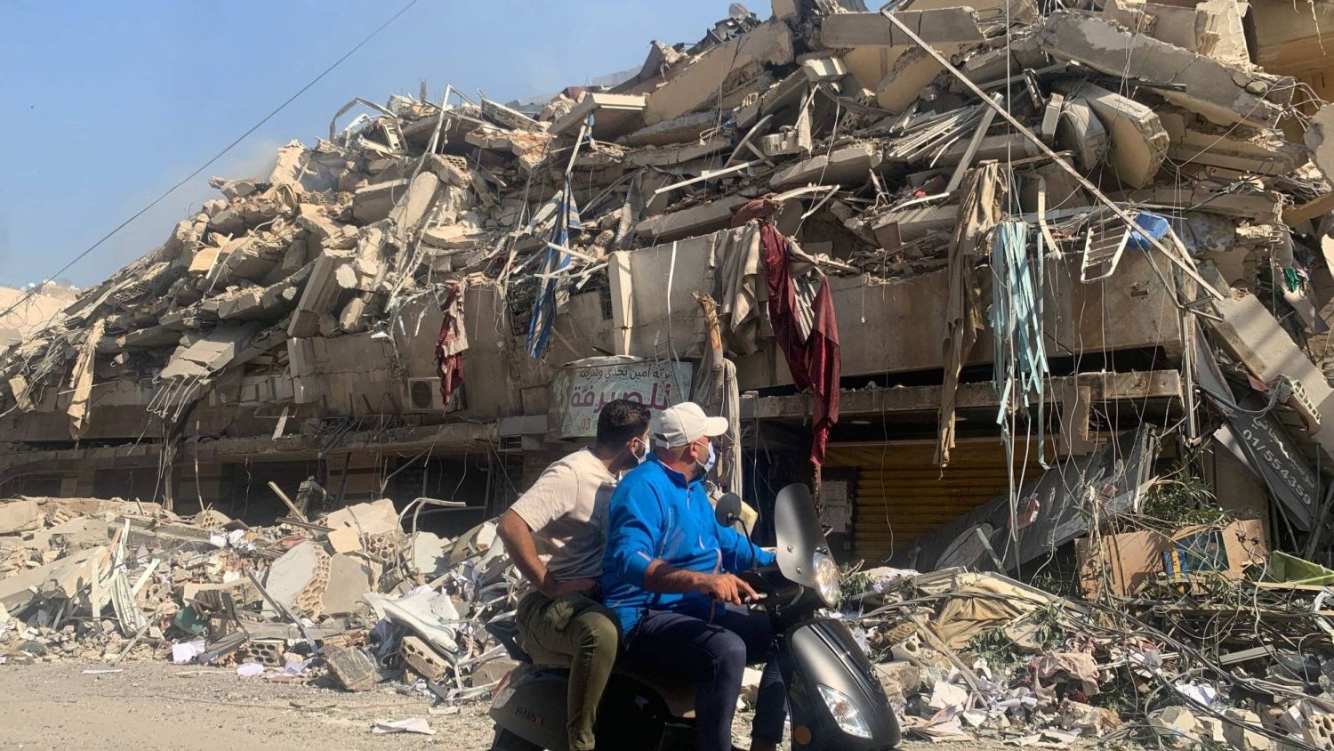 لبنانيان يستقلان دراجة نارية يمران بمبان دمرها القصف الإسرائيلي في حارة حريك بضاحية بيروت الجنوبية