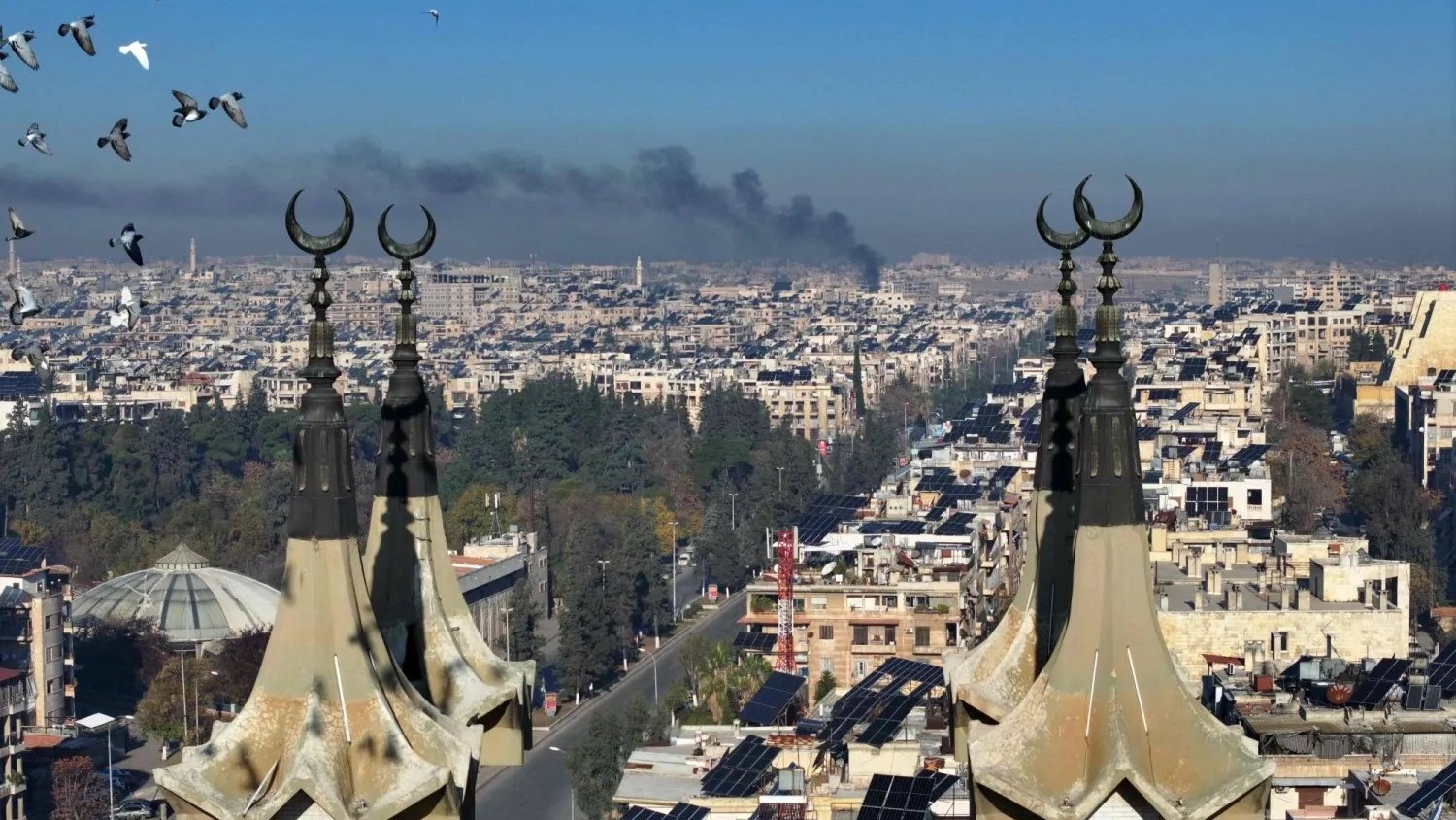 صورة جوية لجانب من مدينة حلب في شمال غربي سوريا مع تصاعد الدخان بعد دخول فصائل مسلحة إلى المدينة