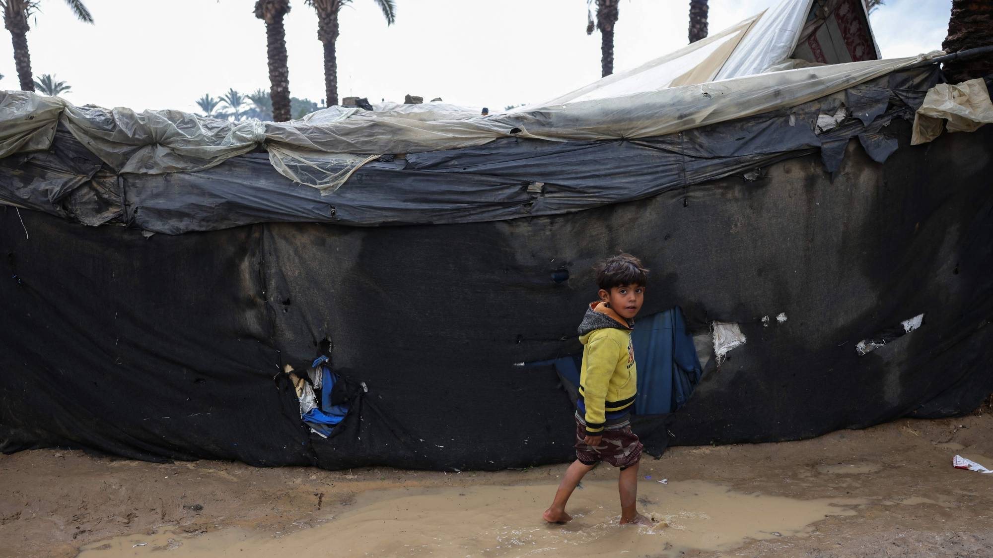 طفل فلسطيني يسير في منطقة غمرتها المياه بعد هطول أمطار غزيرة بمخيم للنازحين وسط قطاع غزة