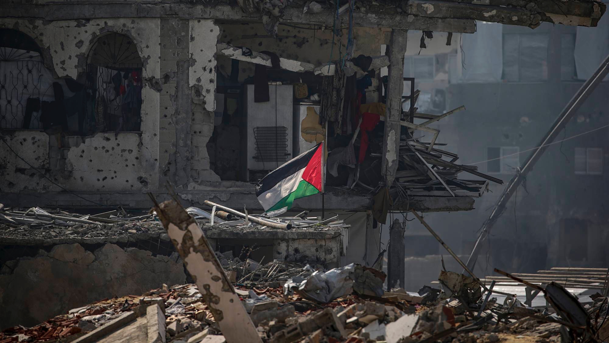 علم فلسطيني يرفرف بجوار مأوى لأسرة فلسطينية أقيمت بين أنقاض المباني المدمرة في مخيم جباليا للاجئين شمال قطاع غزة في 17 شباط (فبراير) 2025