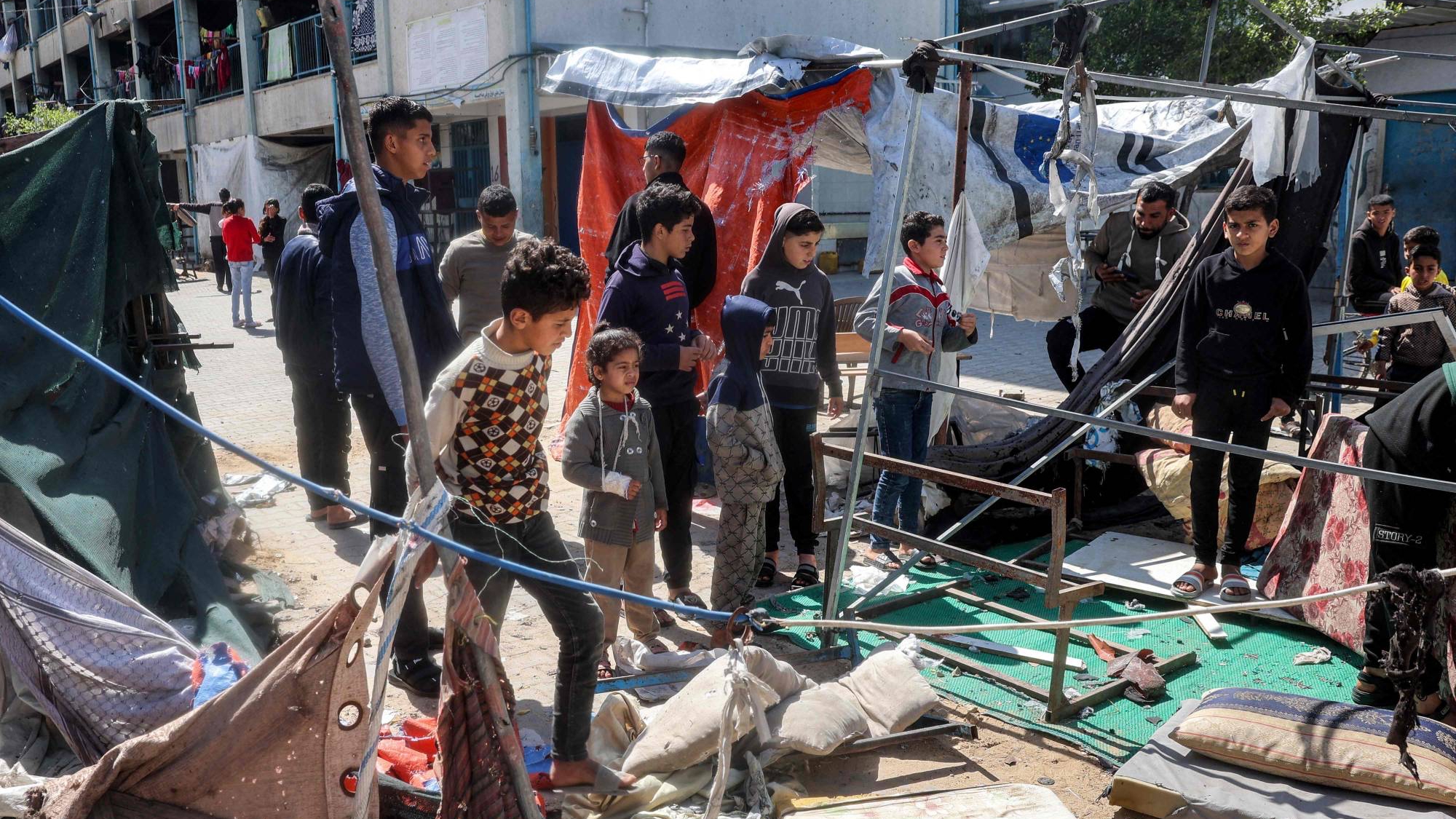 أطفال يقفون في موقع خيمة أصابها قصف إسرائيلي في مخيم النصيرات بقطاع غزة في 24 آذار (مارس) 2025