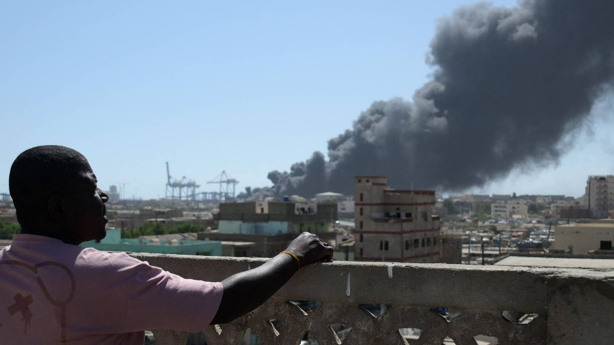 رجل يشاهد تصاعد الدخان بعد الهجوم على ميناء بورتسودان