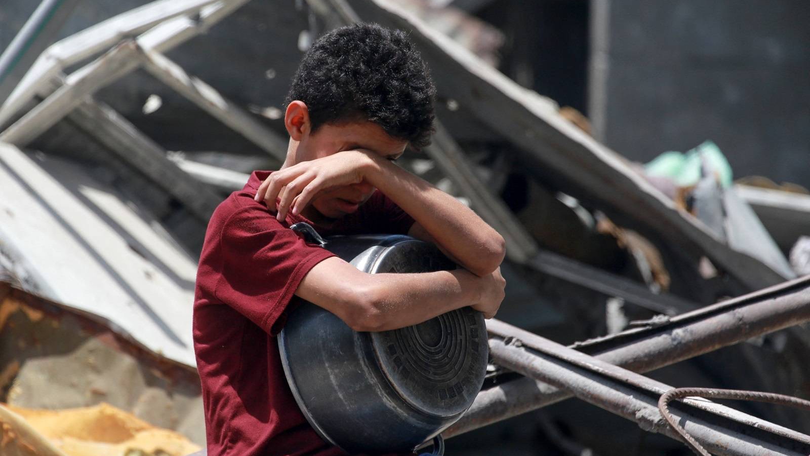 طفل فلسطيني يترقب دوره في حصص من الطعام المطبوخ بمركز توزيع خيري في جباليا شمال غزة 