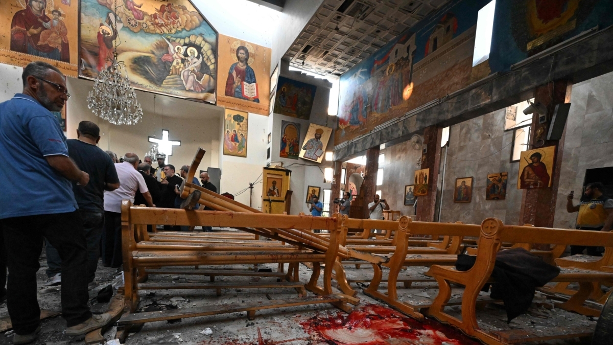 رجل ينظر إلى بقع من الدماء بينما يقوم رجال الإنقاذ بفحص الأضرار في موقع الهجوم الانتحاري في كنيسة مار إلياس بدمشق في 22 حزيران (يونيو) 2025