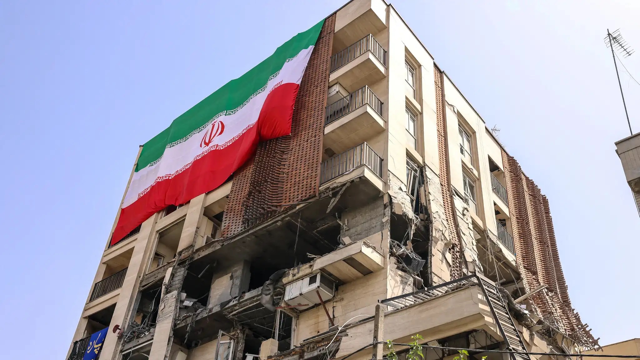 مبنى سكني تعرض لغارة إسرائيلية مغطى بعلم إيراني كبير في طهران في 25 حزيران (يونيو) 2025