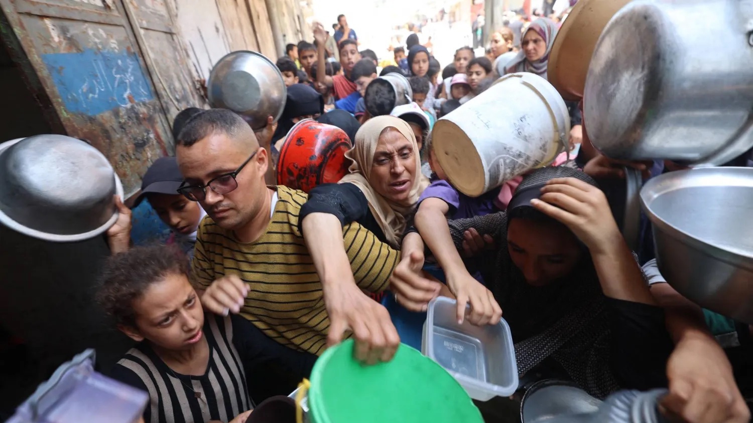 فلسطينيون يتدافعون عند نقطة توزيع المساعدات الغذائية في النصيرات وسط قطاع غزة