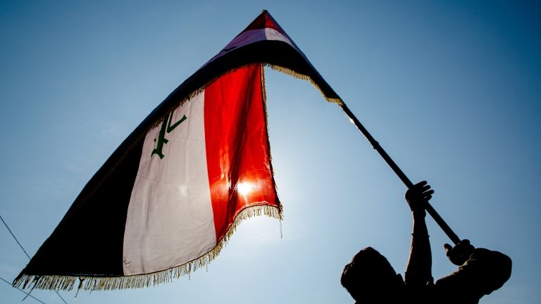 رجل يلوح بعلم عراقي