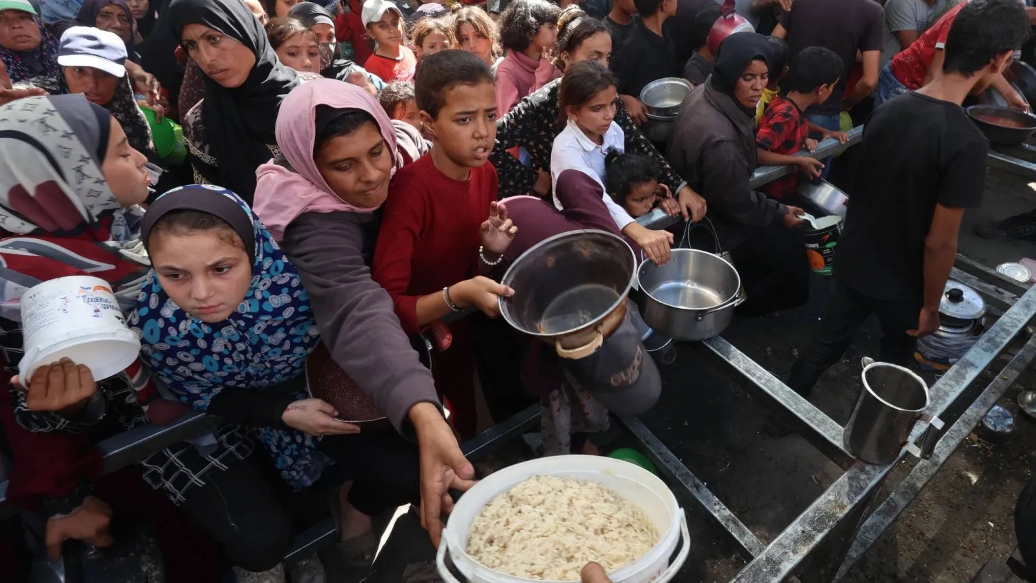 فلسطينيون يتجمعون لتسلم حصص غذائية من مطبخ خيري في مخيم النصيرات للاجئين