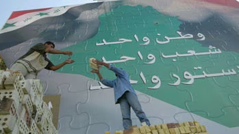 عاملان تحت إعلان عملاق رفع في بغداد إبان الاستفتاء على الدستور