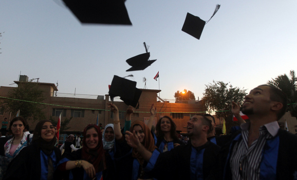 طلاب يرمون قبعاتهم في الهواء احتفالاً بتخرجهم من إحدى جامعات بغداد