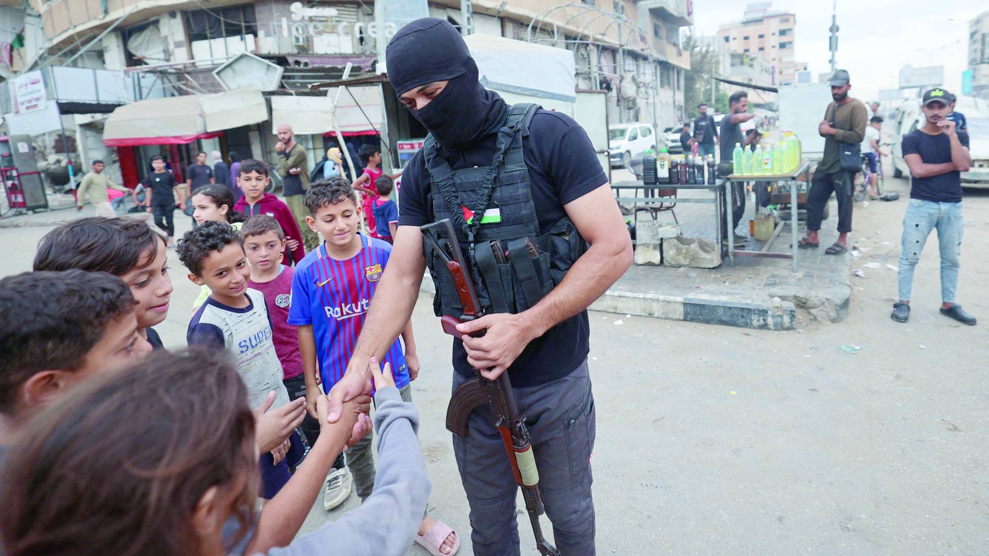 أحد عناصر قوات الأمن الداخلي لحركة «حماس» يُسلم على أطفال في مخيم النصيرات للاجئين وسط غزة
