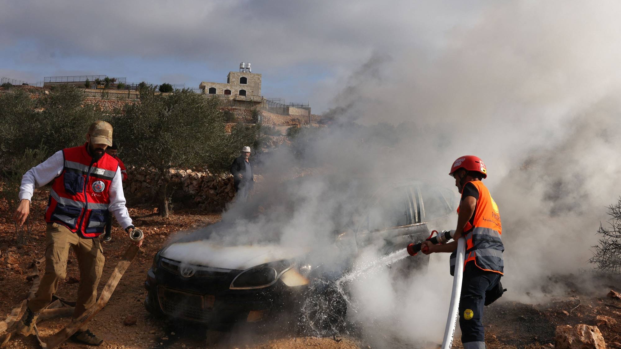 مسعفون فلسطينيون يخمدون النيران في سيارة أضرم فيها مستوطنون إسرائيليون النار في محاولة لتعطيل قطاف الزيتون في ترمسعيا