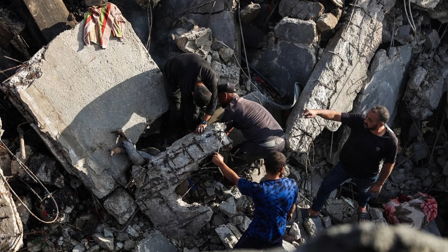 فلسطينيون يستعيدون جثة من تحت أنقاض منزل دُمر في غارة إسرائيلية ليلية على مدينة غزة