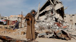 رجل فلسطيني يسير بالقرب من أنقاض المنازل التي دمرت خلال الهجوم الإسرائيلي على رفح، جنوب قطاع غزة - 13 مارس/آذار 2025 - Reuters