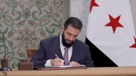 رئيس المرحلة الانتقالية في سوريا، أحمد الشرع، يوقع على مسوّدة الإعلان الدستوري السوري. - Reuters