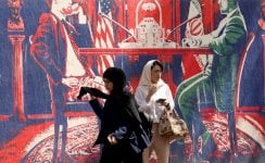 نساء يسيرن بجوار جدارية مناهضة للولايات المتحدة بالقرب من السفارة الأمريكية السابقة في طهران، إيران، 11 مايو/أيار 2025 - EPA