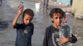 طفلان في غزة يحملان أوعية فيها ماء - Reuters