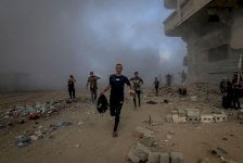 مجموعة من الأشخاص يحاولون النجاة من القصف الإسرائيلي، يركضون وسط أبنية مدمرة وداخن كثيف ناجم عن القصف الإسرائيلي على مدينة غزة. - Anadolu via Getty Images