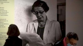 أحد الزوّار إلى جانب صورة للفيلسوفة والمنظّرة السياسية الألمانية-الأمريكية حنّة آرنت خلال العرض التمهيدي للصحافة لمعرض 