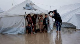 أربعة أطفال وامرأتان في خيمة تحت المطر - AFP via Getty Images