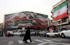 امرأة إيرانية تعبر طريقا بالقرب من لوحة إعلانية كُتب عليها