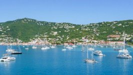 مراكب بيضاء على صفحة مياه زرقاء، في حضن تلال خضراء مرصّعة بمبان بيضاء اللون، في جزيرة سانت توماس - Getty Images