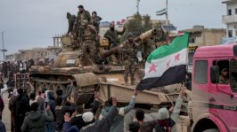 عناصر من الجيش السوري في دير حافر بعد انسحاب قوات سوريا الديمقراطية (قسد)، يقفون على ظهر دبابة ويحملون العلم السوري ذو النجوم الحمراء الثلاثة وحولهم حشد من الناس. - EPA