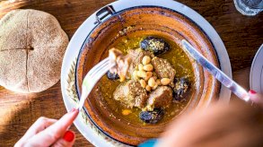 طبق من حساء اللحم بالبرقوق وسيدة تظهر أصابعها وهي تأكل منه بأدوات المنضدة - Getty Images