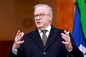 رئيس الوزراء الأسترالي أنتوني ألبانيز يتحدث خلال مؤتمر صحفي في كانبيرا في 11 أغسطس/آب 2025. يرتدي بدلة رسمية كحلية اللون ويحرك يديه أثناء حديثه وخلفه العلم الأسترالي. - AFP via Getty Images