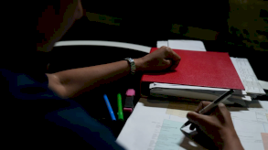 يد إنسان تمسك قلماً وتكتب على ورق - Anahita Sachdev/BBC