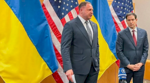 أندري يرماك (يسار)، يرتدي بدلة رسمية رمادية اللون وقميصاً أبيض وربطة عنق رمادية مخططة بالأسود، بجانبه يقف وزير الخارجية الأمريكي ماركو روبيو مرتدياً بدلة رسمية رمادية اللون أيضاً وقميصاً أبيض وربطة عنق تبدو حمراء اللون، يبدو أنهما يتحدثان وخلفهما أربعة أعلام، علمان للولايات المتحدة، وعلمان لأوكرانيا - Reuters