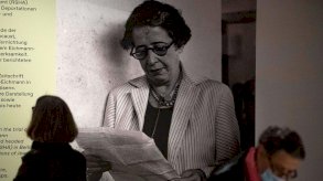 أحد الزوّار إلى جانب صورة للفيلسوفة والمنظّرة السياسية الألمانية-الأمريكية حنّة آرنت خلال العرض التمهيدي للصحافة لمعرض 