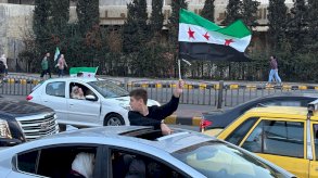 يرفع طفل سوري علم سوريا الجديد خلال خروجه من نافذة إحدى السيارات. - BBC