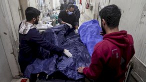 مسعفون يضعون جثة في كيس مخصص للجثث في أحد المستشفيات خلال موجة هجمات شنتها القوات الحكومية وقوات سوريا الديمقراطية بقيادة الأكراد في مدينة حلب شمال سوريا - Reuters