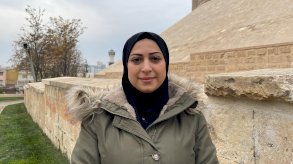 صورة لآية مصطفى. تنظر مباشرة إلى الكاميرا وهي ترتدي حجاباً أسود ومعطفاً شتوياً أخضر. - BBC