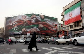 امرأة إيرانية تعبر طريقا بالقرب من لوحة إعلانية كُتب عليها 