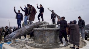 مجموعة من المدنيين يحطمون تمثالاً لمقاتل من قوات سوريا الديمقراطية في مدينة الطبقة بعد سيطرة الجيش السوري عليها، في الطبقة، سوريا. - Reuters