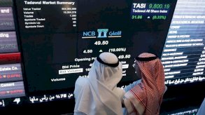 مستثمران يتابعان شاشة التداول في السوق المالية السعودية