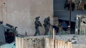 عنصران من القوات الإسرائيلية بزي عسكري يحملان السلاح، أثناء عملية جنين في الضفة الغربية المحتلة، يوجهان السلاح نحو شابين فلسطينيين يرتديان لباساً مدنياً. الصورة التقطت نهاراً. - Reuters