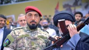 طبطبائي بالزي العسكري لحزب الله وإلى جانبه هاشم صفي الدين يقبل السلاح