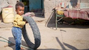 طفل صغير في اليمن يتعافى من سوء التغذية يلعب بإطار © UNICEF/Alaa Noman