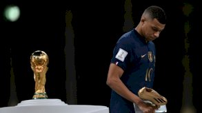 المهاجم الفرنسي كيليان مبابي يمر أمام كأس العالم حاملاً جائزة الحذاء الذهبي لأفضل هداف في مونديال قطر بعد خسارة النهائي أمام الأرجنتين بركلات الترجيح على ملعب لوسيل في الدوحة في 18 ديسمبر 2022