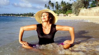 صورة تعود لفبراير من عام 1994 وفيها تمارس الممثلة جوان كولينز التأمل وهي تجلس على حافة المحيط في خليج شوغر في بريدجتاون ببربادوس - Getty Images