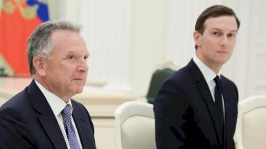 ينظر ستيف ويتكوف وجاريد كوشنر، وكلاهما يرتديان سترتين داكنتين، إلى طاولة مفاوضات في الكرملين. في الخلفية، يرفرف علم روسي. - Reuters