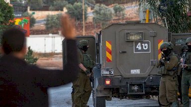 صورة تُظهر جنوداً إسرائيليين يرفعون سلاحهم باتجاه فلسطيني يرفع يديه في الضفة الغربية - AFP via Getty Images