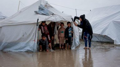 أربعة أطفال وامرأتان في خيمة تحت المطر - AFP via Getty Images