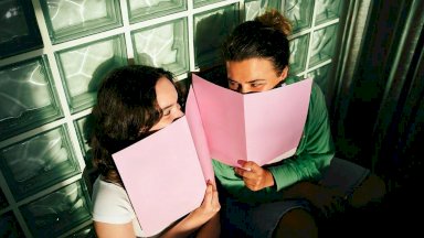 فتاتان تبتسمان خلف دفتريهما - Getty Images