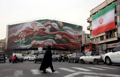 امرأة إيرانية تعبر طريقا بالقرب من لوحة إعلانية كُتب عليها